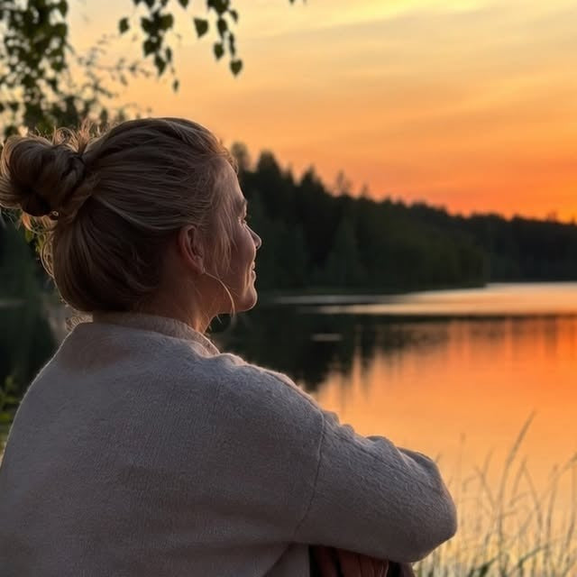 Nainen katselee järvimaisemaa auringonlaskussa