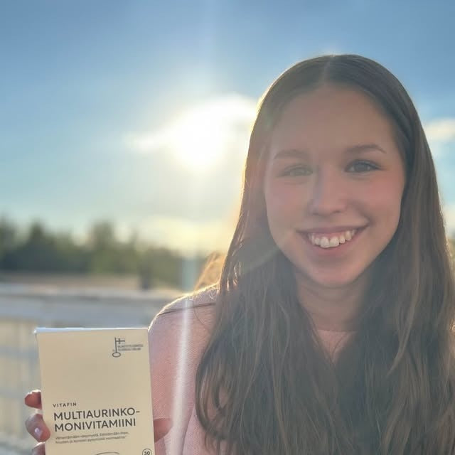 Asiakas pitelee VitaFin MultiAurinko-monivitamiinipakkausta ulkona